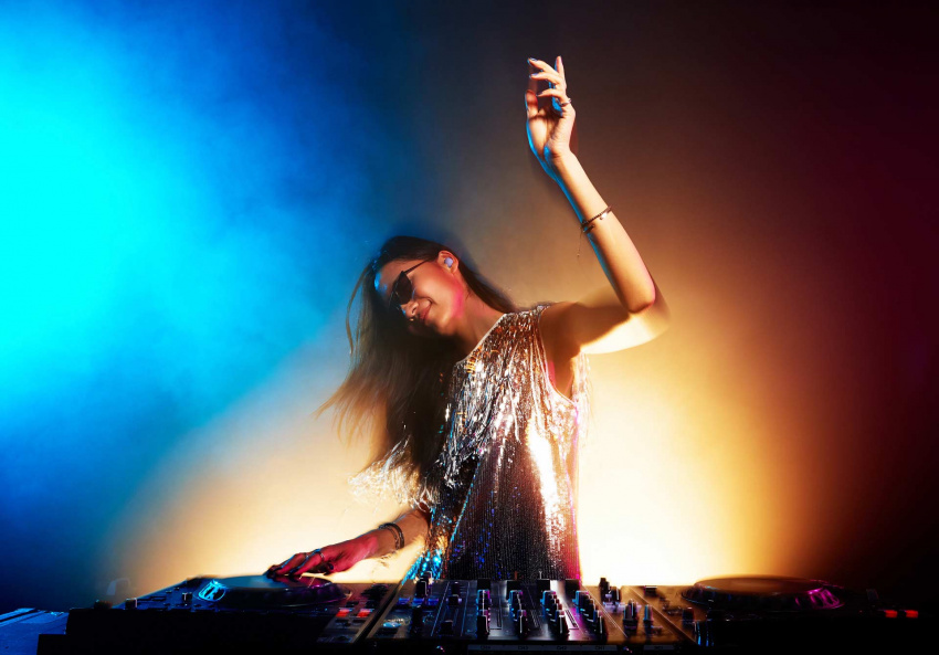 A woman enjoying herself while DJing at a party with Buds2 Pro in her left ear.